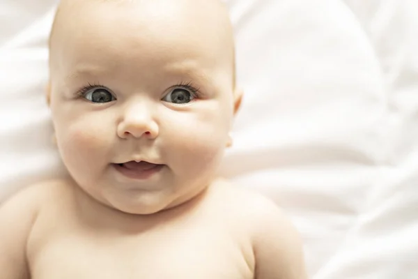 Une jolie petite fille sur un lit blanc à la maison — Photo