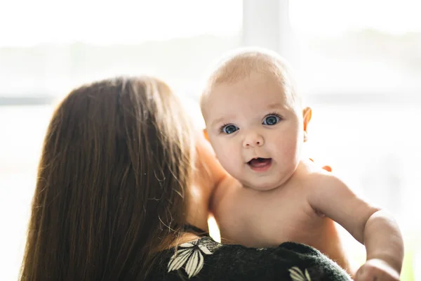 Un retrato de bebé feliz con madre alegre en la ventana de casa — Foto de Stock