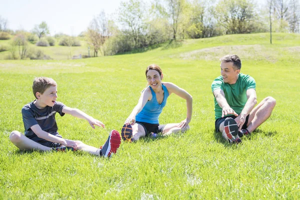 Rodzice z dziećmi sstretching razem poza — Zdjęcie stockowe