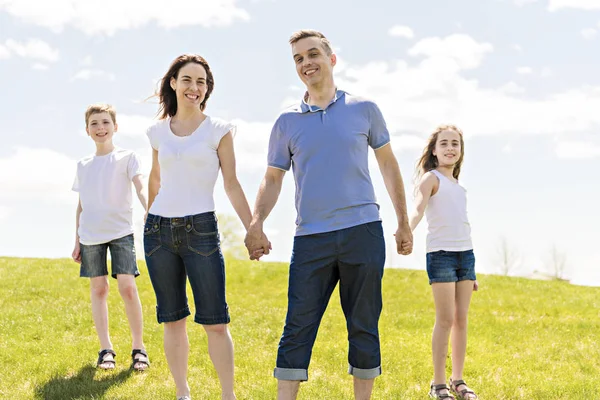 Family of four outdoors in a field having fun — Stock Photo, Image