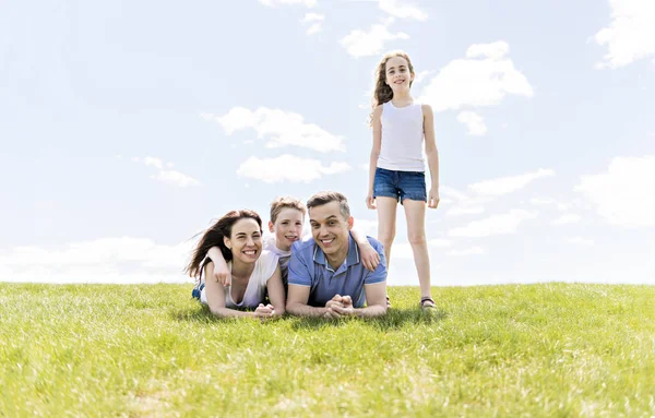 Family of four outdoors in a field having fun — Stock Photo, Image