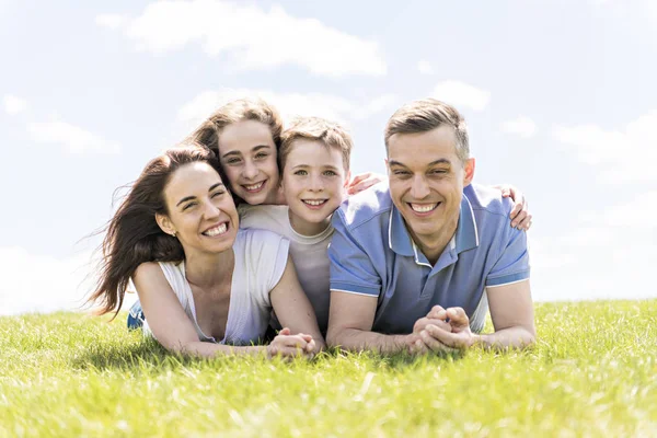 Family of four outdoors in a field having fun — Stock Photo, Image