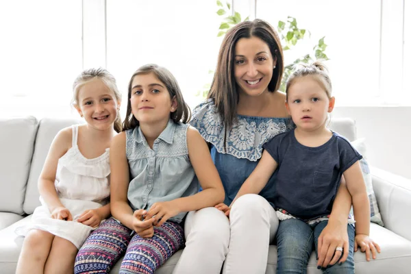 Gelukkig jonge vrouw met kinderen op de sofa thuis — Stockfoto