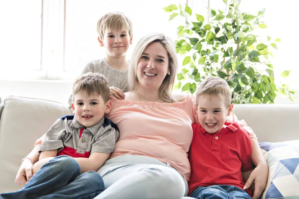 Gelukkig jonge vrouw met kinderen op de sofa thuis — Stockfoto