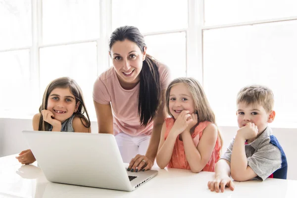 Nauczyciel z grupą dzieci w wieku szkolnym z laptopa z przodu — Zdjęcie stockowe