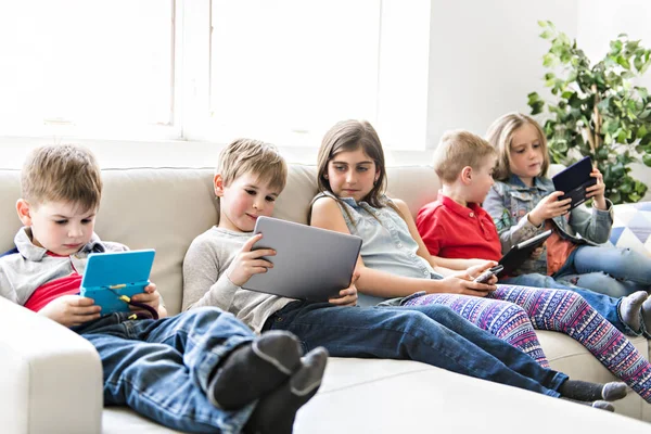 グループの子供に座ってソファ自宅とのタブレット、ビデオゲーム — ストック写真