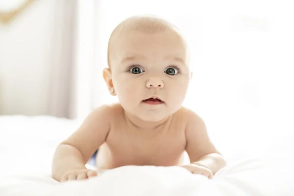 Una linda niña en una cama blanca en casa — Foto de Stock