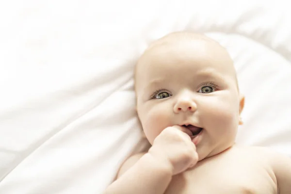 Une jolie petite fille sur un lit blanc à la maison — Photo