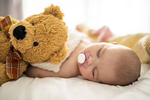 クマと自宅の白いベッドで寝ている 4 ヶ月の赤ちゃん — ストック写真