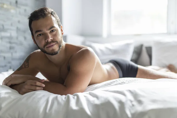 Młody człowiek z Meksyku, shirtless w białe łóżko — Zdjęcie stockowe