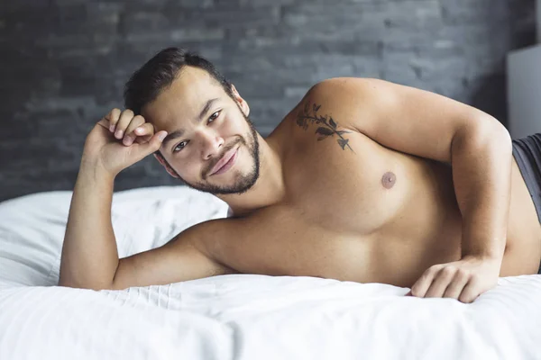 A young mexican man shirtless in white bed