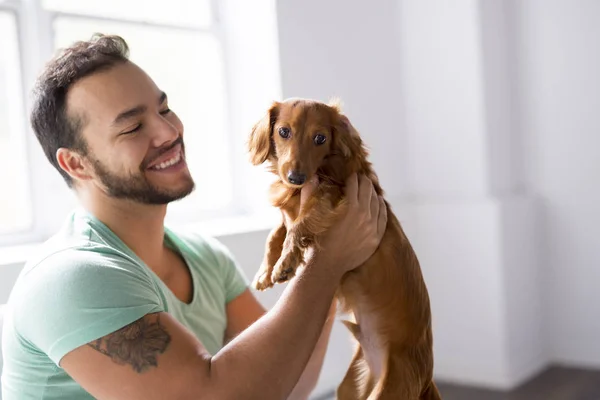 Joven mexicano en casa sentado en el sofá con el perro — Foto de Stock