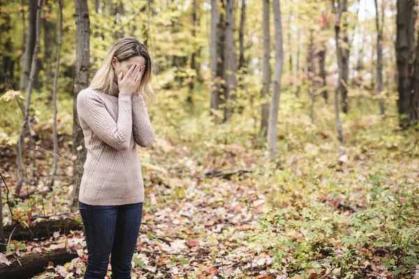 Een trieste vrouw in het park tijdens het herfstweer verstopt zich gezicht in de hand, zich verschrikkelijk depressief voelen. — Stockfoto