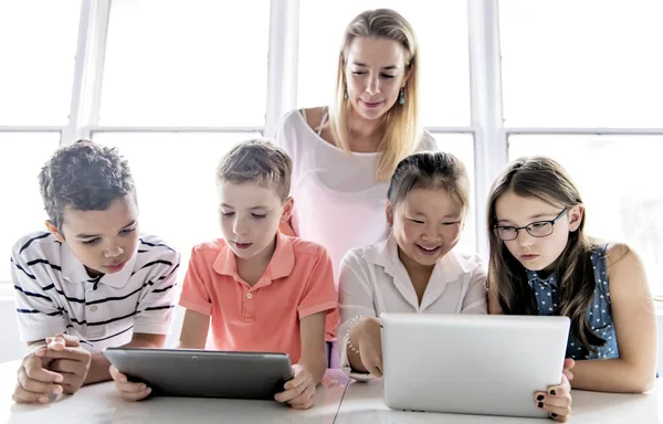 Παιδί με tablet τεχνολογίας και φορητό υπολογιστή στην τάξη δάσκαλος στο παρασκήνιο — Φωτογραφία Αρχείου