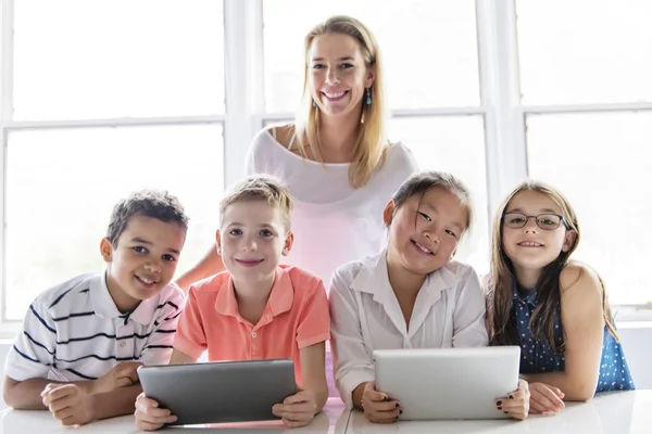 Criança com tecnologia tablet e computador portátil em sala de aula professor em segundo plano — Fotografia de Stock