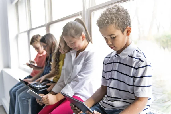 Grupo de niños curiosos viendo cosas en la pantalla de la tableta —  Fotos de Stock
