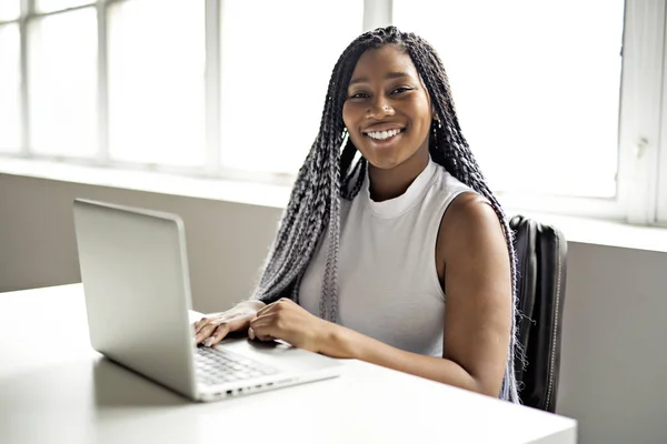 Teenager ved skrivebordet på hendes kontor med laptop - Stock-foto