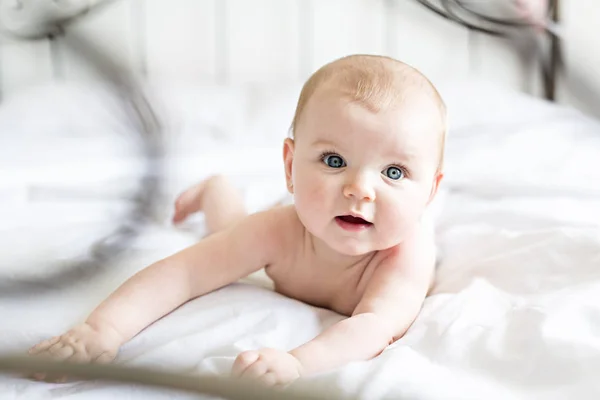 Menina bebê em roupa de cama branca em casa olhar agradável — Fotografia de Stock