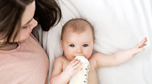 Mère nourrissant bébé avec une bouteille de lait au lit à la maison — Photo