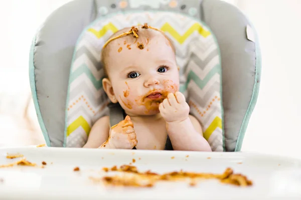 Kleine baby eet haar eten en maakt er een puinhoop van — Stockfoto