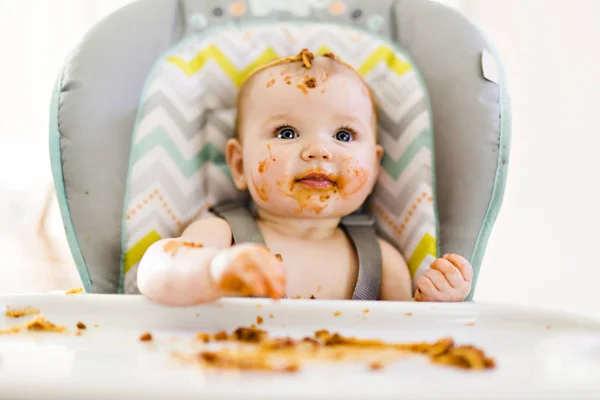 Piccolo bambino mangiare la sua cena e fare un pasticcio — Foto Stock