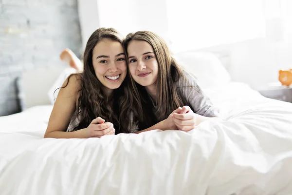 Friends in pajamas sitting in bed at home relaxing. — Stock Photo, Image