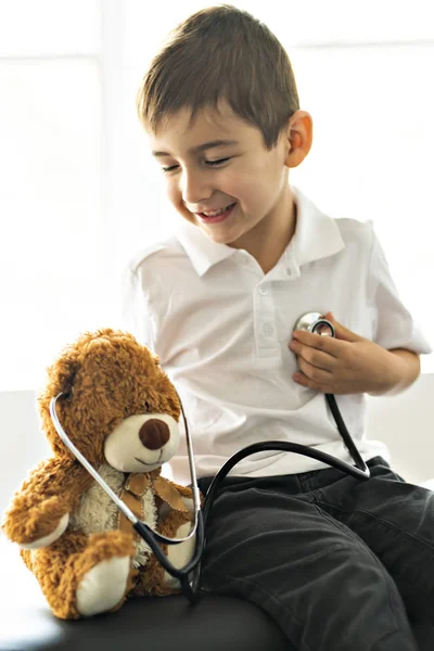 Мальчик-врач играет и лечит медведя в педиатрии — стоковое фото