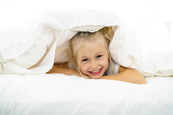 Egy vidám kis lány az ágyban, szórakozás — Stock Fotó