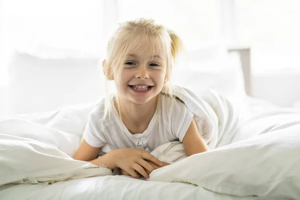 Une petite fille joyeuse au lit s'amuser — Photo