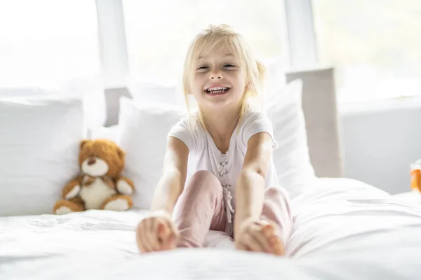 Веселая маленькая девочка в постели веселится — стоковое фото