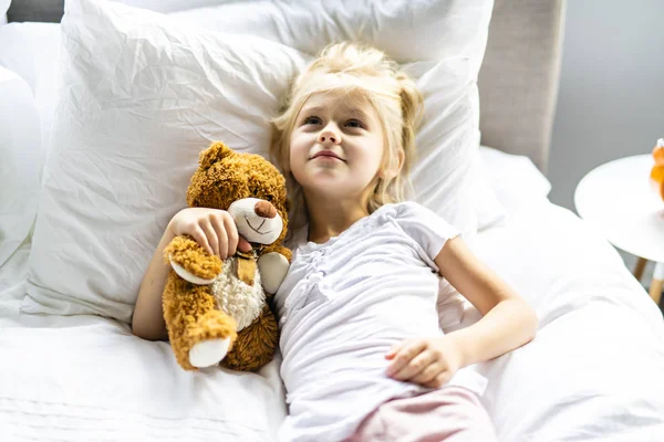 Ein fröhliches kleines Mädchen im Bett entspannen — Stockfoto