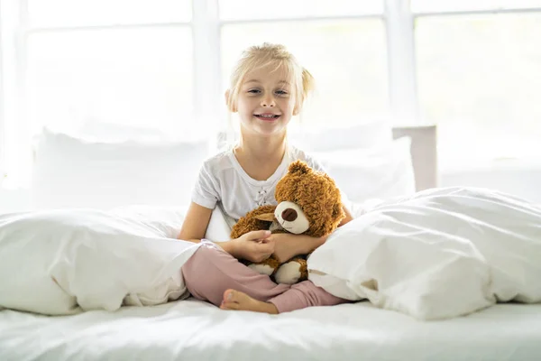 Ένα χαρούμενο μικρό κορίτσι στο κρεβάτι έχοντας διασκέδαση — Φωτογραφία Αρχείου