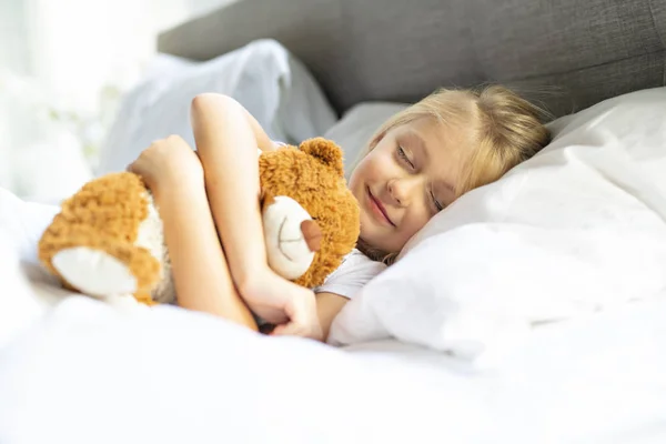 Ένα μικρό κορίτσι στο κρεβάτι στον ύπνο και όνειρα με αρκουδάκι, — Φωτογραφία Αρχείου