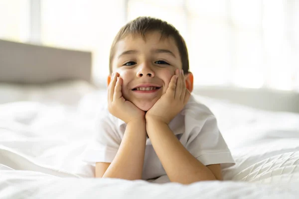 Un lindo niño de cuatro años en ropa de cama blanca —  Fotos de Stock