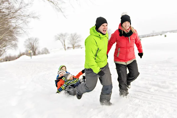 Χαριτωμένο οικογένεια τράβηγμα έλκηθρο μέσα από το χιονισμένο τοπίο — Φωτογραφία Αρχείου