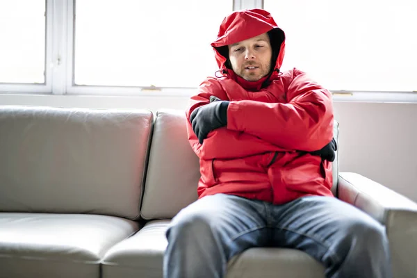 Un uomo con vestiti caldi che sente il freddo dentro casa sul divano — Foto Stock