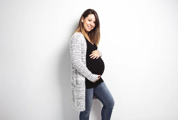Портрет счастливой беременной женщины с руками на животе на белом фоне — стоковое фото