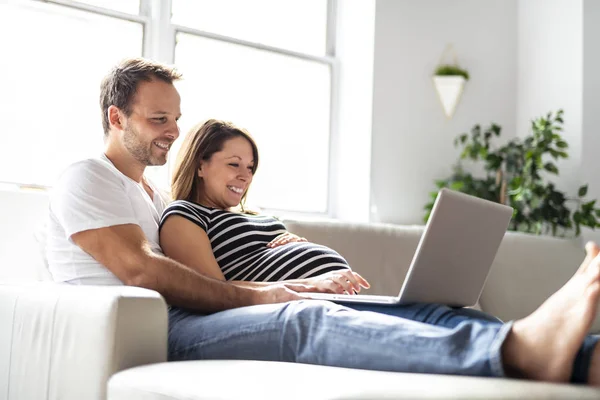 Pár s těhotnou ženou společně pomocí přenosného počítače — Stock fotografie