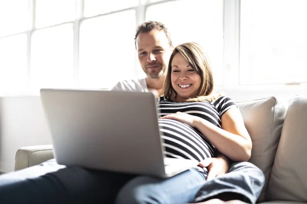 Um casal com mulher grávida usando computador portátil juntos — Fotografia de Stock