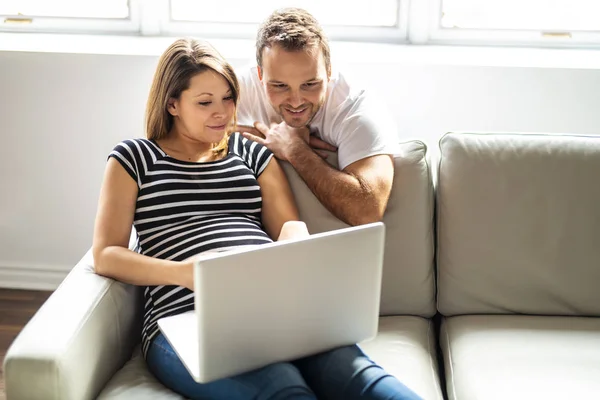 Un couple avec une femme enceinte utilisant un ordinateur portable ensemble — Photo