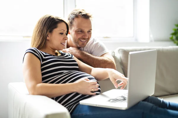 Ένα ζευγάρι με έγκυο γυναίκα χρησιμοποιεί το φορητό υπολογιστή μαζί — Φωτογραφία Αρχείου