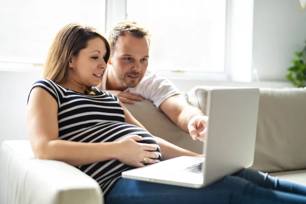 Una pareja con la mujer embarazada usando ordenador portátil juntos —  Fotos de Stock