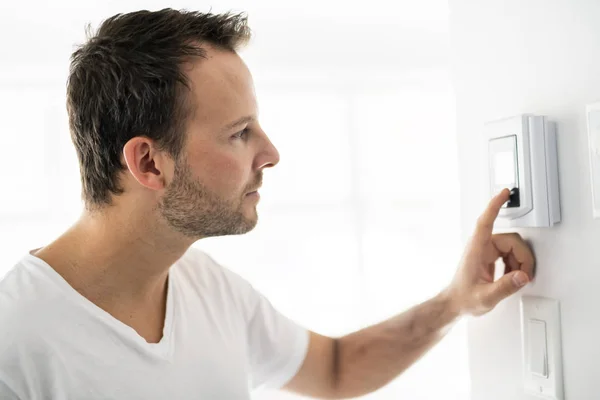Ένας άνθρωπος Ρυθμίστε το θερμοστάτη στο σπίτι — Φωτογραφία Αρχείου