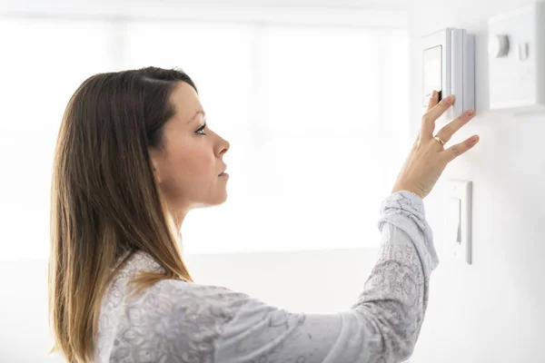 Une femme a réglé le thermostat à la maison — Photo