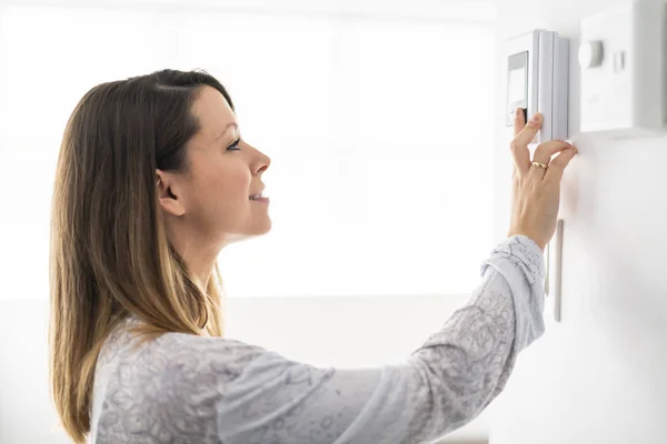 Eine Frau stellte das Thermostat am Haus ein — Stockfoto