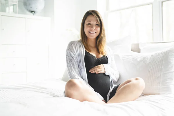 Una mujer embarazada bastante joven acostada en la cama —  Fotos de Stock