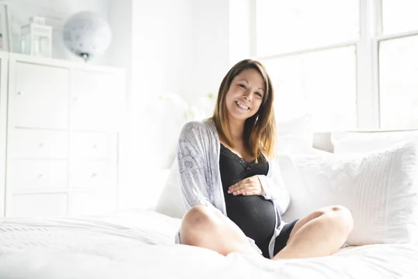 Una bella giovane donna incinta sdraiata sul letto — Foto Stock