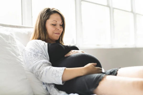 Eine hübsche junge schwangere Frau liegt im Bett — Stockfoto