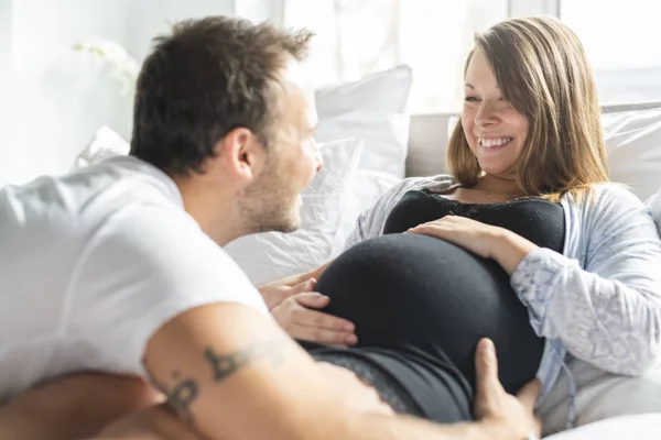 Um pais na cama esperando um bebê pequeno, momentos românticos para casal grávida — Fotografia de Stock