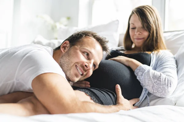 Um pais na cama esperando um bebê pequeno, momentos românticos para casal grávida — Fotografia de Stock